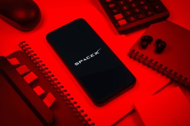 Prag, Çek Cumhuriyeti - 08 18 2025: SpaceX logosunu gösteren bir cep telefonu ile ofis malzemeleri düzenlemesi. SpaceX uzay keşfi ve roket fırlatmaları için özel bir şirkettir..