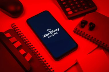 Prag, Çek Cumhuriyeti - 08 18 2025: Merkezde Walt Disney logosunu gösteren bir cep telefonu ile ofis malzemeleri düzenlemesi. Walt Disney film, park ve medya için bir eğlence şirketidir..
