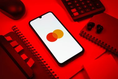 Prag, Çek Cumhuriyeti - 08 18 2025: Merkezde Mastercard logosu sergilenen bir cep telefonu ile ofis malzemeleri düzenlemesi. Mastercard ödeme kartları ve hizmetler sağlayan bir finans şirketidir..