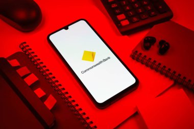 Prag, Çek Cumhuriyeti - 08 18 2025: Merkezinde Commonwealth Bank logosu bulunan bir cep telefonu ile ofis malzemeleri düzenlemesi. Commonwealth Bank, Avustralya 'da finansal hizmetler sağlayan bir bankadır..