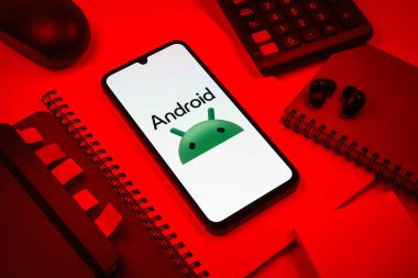 Prag, Çek Cumhuriyeti - 08 18 2025: Merkezde Android logosunu gösteren bir cep telefonu ile ofis malzemeleri düzenlemesi. Android akıllı telefonlar ve tabletler için mobil bir işletim sistemidir..