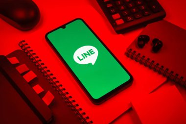 Prag, Çek Cumhuriyeti - 08 18 2025: Merkezinde hat logosu sergilenen bir cep telefonu ile ofis malzemeleri düzenlemesi. Line aramalar, mesajlar ve çokluortam paylaşımı için bir mesajlaşma uygulamasıdır.