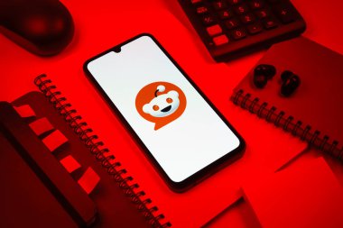 Prag, Çek Cumhuriyeti - 08 18 2025: Merkezde Reddit logosunu gösteren bir cep telefonu ile ofis malzemeleri düzenlemesi. Reddit tartışma, haber ve toplum içeriği için bir platformdur.