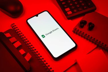 Prag, Çek Cumhuriyeti - 08 18 2025: Merkezde Google Sheets logosunu gösteren bir cep telefonu ile ofis malzemeleri düzenlemesi. Google Sayfalar tablo oluşturmak ve yönetmek için bir platformdur.