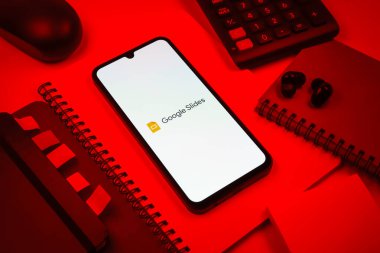 Prag, Çek Cumhuriyeti - 08 18 2025: Merkezde Google Slides logosunu gösteren bir cep telefonu ile ofis malzemeleri düzenlemesi. Google Slides sunumlar ve slayt gösterileri oluşturmak için bir platformdur.