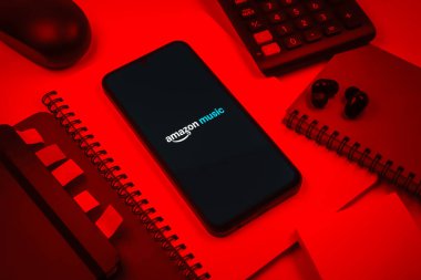 Prag, Çek Cumhuriyeti - 08 18 2025: Merkezde Amazon Müzik logosu sergilenen bir cep telefonu ile ofis malzemeleri düzenlemesi. Amazon Müzik müzik müzik için bir platformdur..