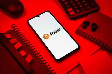Prag, Çek Cumhuriyeti - 08 18 2025: Avast logosunu gösteren bir cep telefonu ile ofis malzemeleri düzenlemesi. Avast antivirüs ve siber güvenlik için bir platformdur.