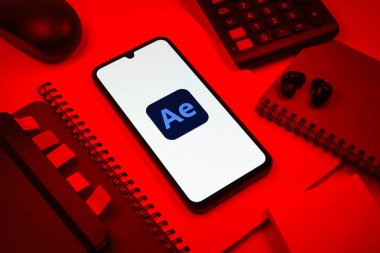 Prag, Çek Cumhuriyeti - 08 18 2025: Ofis malzemelerinin merkezde After Effects logosu sergilenen bir cep telefonu ile düzenlenmesi. After Effects hareket grafikleri ve görsel efektler için bir yazılımdır..