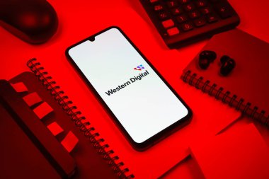 Prag, Çek Cumhuriyeti - 08 18 2025: Merkezde Batı Dijital logosunu gösteren bir cep telefonu ile ofis malzemeleri düzenlemesi. Western Digital, veri depolama cihazları ve çözümleri üreten bir şirkettir..