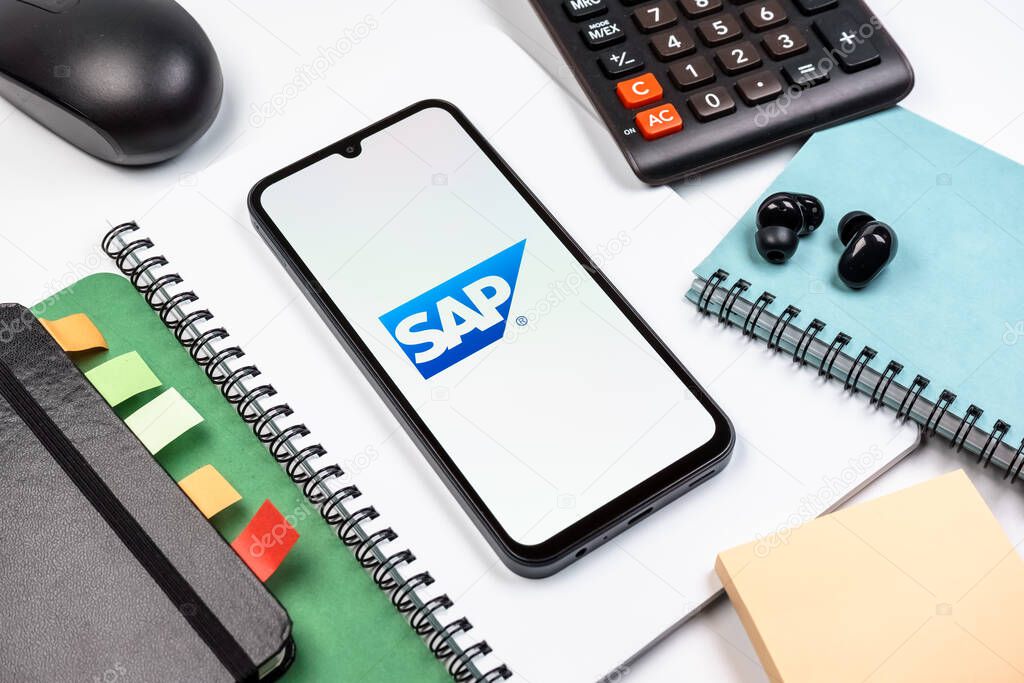 Prague, Czechia - 08 18 2025: An arrangement of office supplies with a mobile phone in the center displaying SAP logo. SAP is a software company providing enterprise applications and solutions.