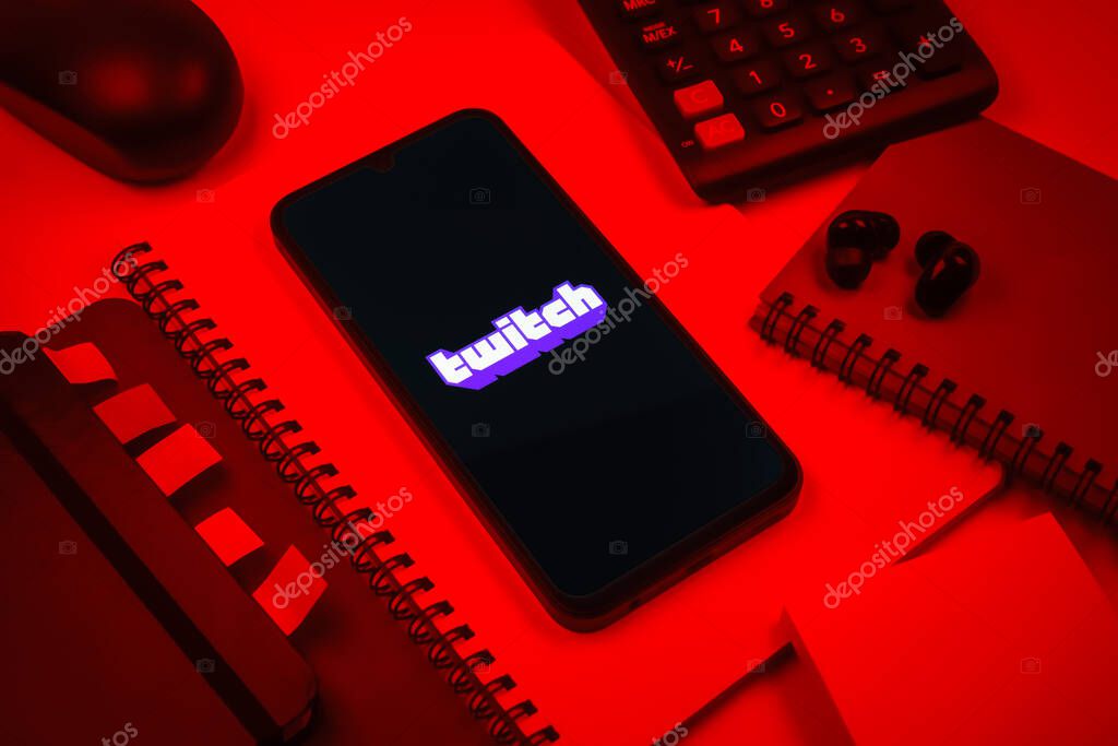 Prague, Czechia - 08 18 2025: An arrangement of office supplies with a mobile phone in the center displaying Twitch logo. Twitch is a platform for live streaming games and content.
