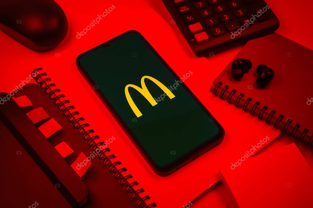 Prague, Czechia - 08 18 2025: An arrangement of office supplies with a mobile phone in the center displaying McDonalds logo. McDonalds is a fast-food chain serving burgers, fries, and more.