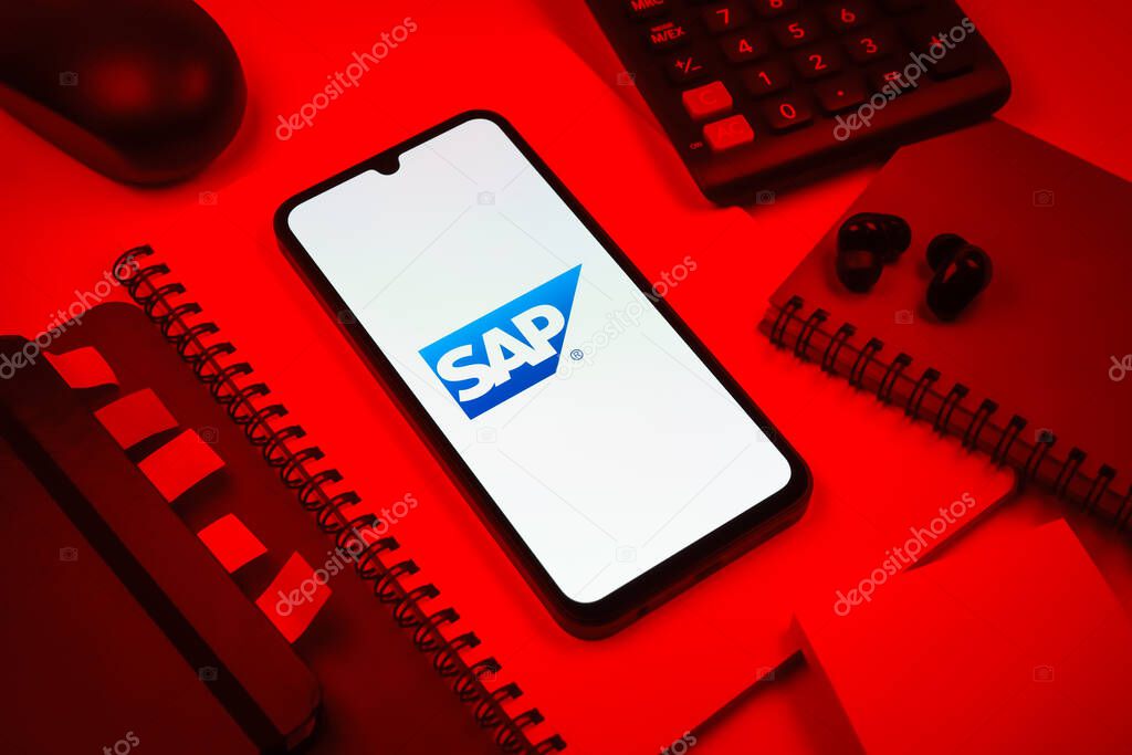 Prague, Czechia - 08 18 2025: An arrangement of office supplies with a mobile phone in the center displaying SAP logo. SAP is a software company providing enterprise applications and solutions.