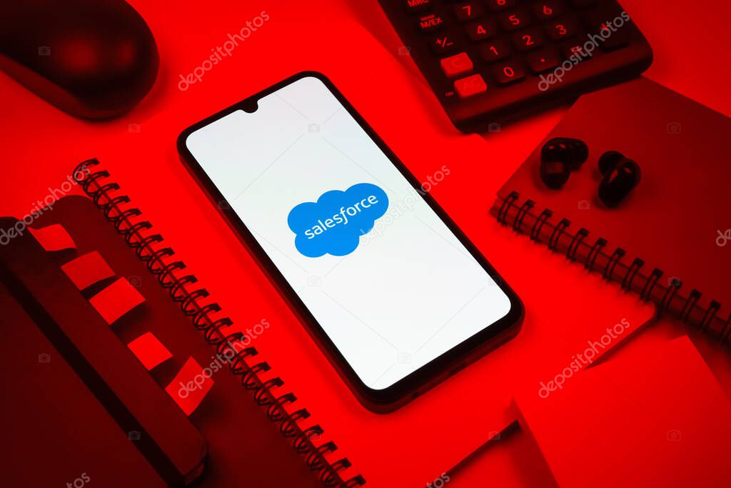 Prague, Czechia - 08 18 2025: An arrangement of office supplies with a mobile phone in the center displaying Salesforce logo. Salesforce is a platform for customer relationship management and cloud services.