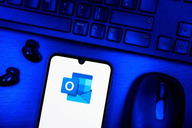 Prag, Çek Cumhuriyeti - 08 09 2025: Outlook logosunu gösteren bir telefonun olduğu bir masanın yukarıdan görünüşü. Outlook iletileri göndermek ve yönetmek için bir e- posta platformudur.