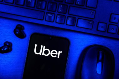 Prague, Czechia - 08 09 2025: A top-down view of a desk with a phone displaying the Uber logo. Uber is a ride-hailing app for transportation and delivery services.