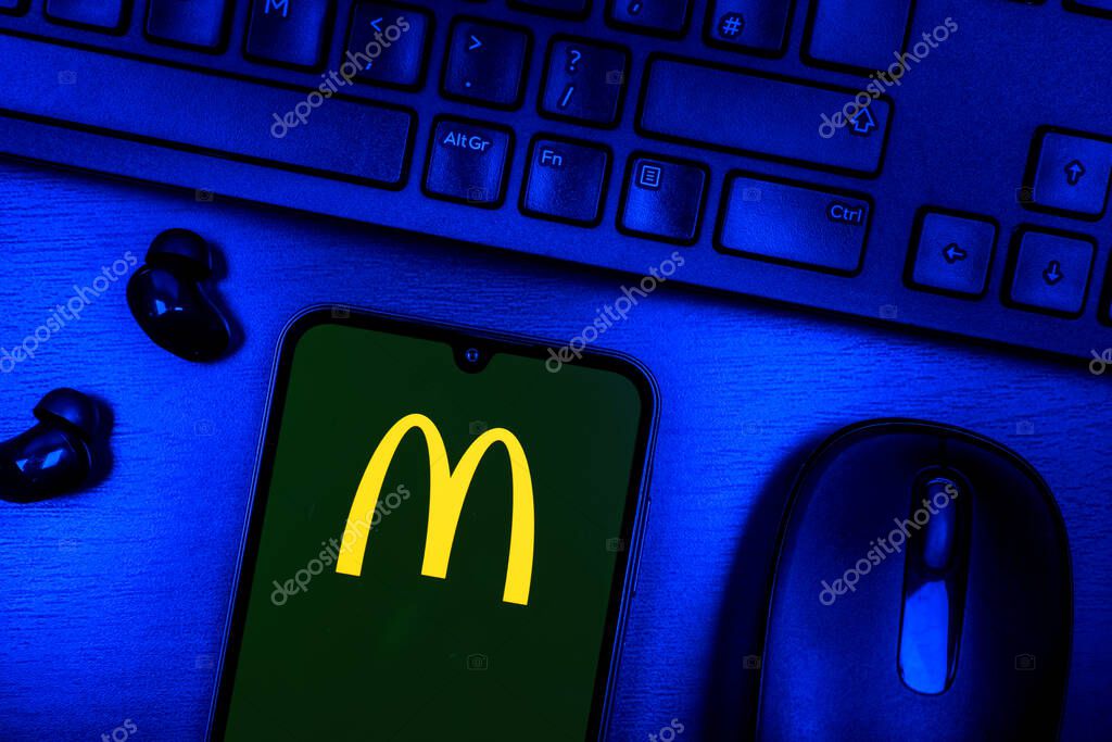 Prague, Czechia - 08 09 2025: A top-down view of a desk with a phone displaying the McDonalds logo. McDonalds is a fast-food chain serving burgers, fries, and more.