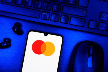 Prague, Czechia - 08 09 2025: A top-down view of a desk with a phone displaying the Mastercard logo. Mastercard is a financial company providing payment cards and services.