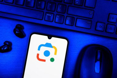 Prague, Czechia - 08 09 2025: A top-down view of a desk with a phone displaying the Google Lens logo. Google Lens is a tool for visual search and information from images.