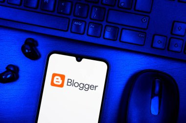 Prague, Czechia - 08 09 2025: A top-down view of a desk with a phone displaying the Blogger logo. Blogger is a platform for creating and publishing blogs.