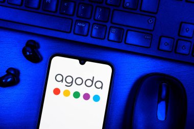 Prague, Czechia - 08 09 2025: A top-down view of a desk with a phone displaying the Agoda logo. Agoda is a platform for booking hotels and travel accommodations.
