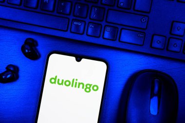 Prague, Czechia - 08 09 2025: A top-down view of a desk with a phone displaying the Duolingo logo. Duolingo is a platform for learning languages interactively.