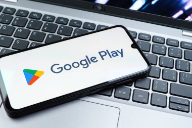 Prag, Çek Cumhuriyeti - 08 01 2025: Dizüstü bilgisayarda bulunan bir cep telefonu Google Play logosunu görüntüler. Google Play uygulamaları, oyunları ve dijital içeriği indirmek için bir platformdur.