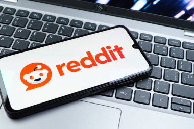 Prag, Çek Cumhuriyeti - 08 01 2025: Dizüstü bilgisayarın üzerinde duran bir cep telefonu Reddit logosunu gösterir. Reddit tartışma, haber ve toplum içeriği için bir platformdur.
