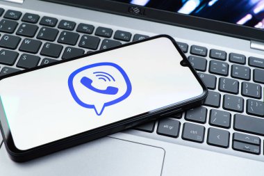 Prag, Çek Cumhuriyeti - 08 01 2025: Dizüstü bilgisayarın üzerinde duran bir cep telefonu Viber logosunu gösteriyor. Viber aramalar, mesajlar ve medya paylaşımı için bir mesajlaşma uygulamasıdır.