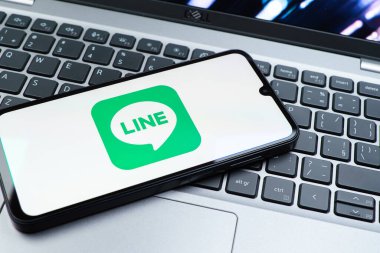 Prag, Çek Cumhuriyeti - 08 01 2025: Dizüstü bilgisayarın üzerinde duran bir cep telefonu Hat logosunu gösterir. Line aramalar, mesajlar ve çokluortam paylaşımı için bir mesajlaşma uygulamasıdır.