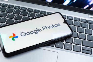 Prag, Çek Cumhuriyeti - 08 01 2025: Laptop klavyesinde duran bir cep telefonu Google Photos logosunu görüntüler. Google Fotoğrafları fotoğraf ve videoları saklamak ve düzenlemek için bir platformdur.