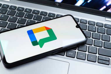 Prag, Çek Cumhuriyeti - 08 01 2025: Dizüstü bilgisayarın üzerinde duran bir cep telefonu Google Chat logosunu görüntüler. Google Chat mesajlaşma ve takım işbirliği için bir platformdur.