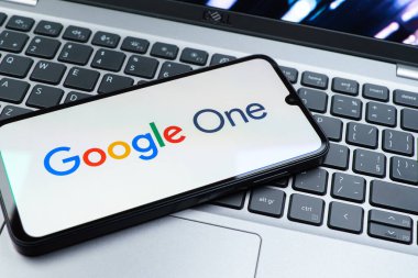 Prag, Çek Cumhuriyeti - 08 01 2025: Dizüstü bilgisayarda bulunan bir cep telefonu Google One logosunu görüntüler. Google 1 bulut depolama ve abonelik hizmetleri için bir platformdur.
