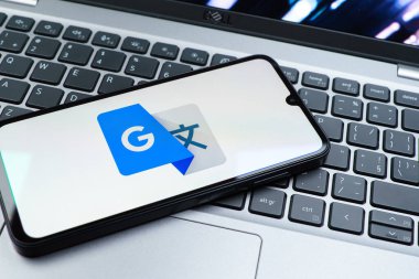 Prag, Çek Cumhuriyeti - 08 01 2025: Dizüstü bilgisayarda bulunan bir cep telefonu Google Translate logosunu görüntüler. Google Çevirisi metni ve konuşmayı diller arası çevirmek için bir platformdur..