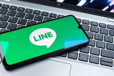 Prag, Çek Cumhuriyeti - 08 01 2025: Dizüstü bilgisayarın üzerinde duran bir cep telefonu Hat logosunu gösterir. Line aramalar, mesajlar ve çokluortam paylaşımı için bir mesajlaşma uygulamasıdır.