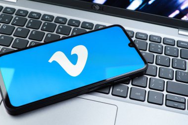Prag, Çek Cumhuriyeti - 08 01 2025: Dizüstü bilgisayarın üzerinde duran bir cep telefonu Vimeo logosunu gösterir. Vimeo, yüksek kaliteli video sunucu ve paylaşımı için bir platformdur.