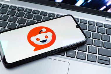 Prag, Çek Cumhuriyeti - 08 01 2025: Dizüstü bilgisayarın üzerinde duran bir cep telefonu Reddit logosunu gösterir. Reddit tartışma, haber ve toplum içeriği için bir platformdur.