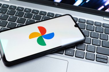 Prag, Çek Cumhuriyeti - 08 01 2025: Laptop klavyesinde duran bir cep telefonu Google Photos logosunu görüntüler. Google Fotoğrafları fotoğraf ve videoları saklamak ve düzenlemek için bir platformdur.