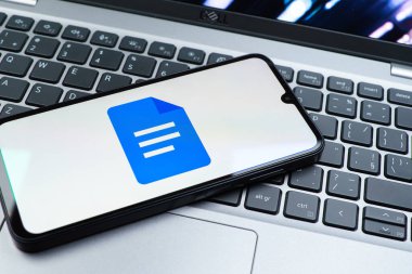 Prag, Çek Cumhuriyeti - 08 01 2025: Dizüstü bilgisayarda bulunan bir cep telefonu Google Docs logosunu görüntüler. Google Docs metin belgeleri oluşturmak ve düzenlemek için bir platformdur.