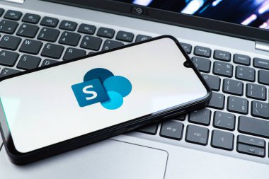 Prag, Çek Cumhuriyeti - 08 01 2025: Dizüstü bilgisayarın üzerinde duran bir cep telefonu Microsoft Sharepoint logosunu gösteriyor. Microsoft Sharepoint işbirliği ve belge yönetimi için bir platformdur.
