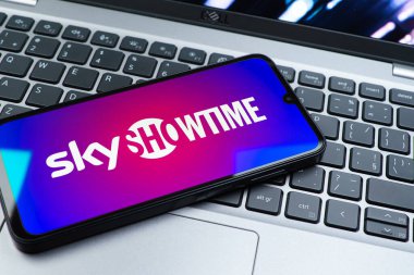 Prag, Çek Cumhuriyeti - 08 01 2025: Dizüstü bilgisayarın üzerinde duran bir cep telefonu SkyShowtime logosunu gösteriyor. SkyShowtime, sinema ve televizyon dizileri için bir yayın platformudur..