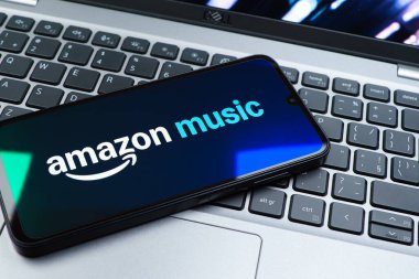 Prag, Çek Cumhuriyeti - 08 01 2025: Laptop klavyesinde uzanan bir cep telefonu Amazon Müzik logosunu gösteriyor. Amazon Müzik müzik müzik için bir platformdur..
