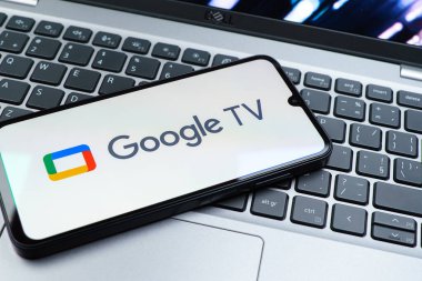 Prag, Çek Cumhuriyeti - 08 01 2025: Laptop klavyesinde uzanan bir cep telefonu Google TV logosunu gösteriyor. Google TV film, program ve uygulamalar için bir platformdur..