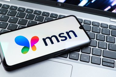 Prag, Çek Cumhuriyeti - 08 01 2025: Dizüstü bilgisayarın üzerinde duran bir cep telefonu MSN logosunu gösterir. MSN haber, e-posta ve çevrimiçi hizmetler için bir platformdur.
