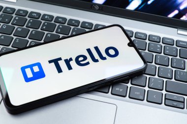 Prag, Çek Cumhuriyeti - 08 01 2025: Dizüstü bilgisayarın üzerinde duran bir cep telefonu Trello logosunu gösterir. Trello, tahta ve görevleri kullanarak proje yönetimi için bir platformdur.