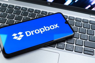 Prag, Çek Cumhuriyeti - 08 01 2025: Laptop klavyesinde duran bir cep telefonu Dropbox logosunu gösterir. Dropbox bulut depolama ve dosya paylaşımı için bir platformdur.