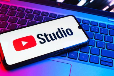 Prag, Çek Cumhuriyeti - 08 01 2025: Laptop klavyesinde duran bir cep telefonu Youtube Stüdyo logosunu görüntüler. Youtube Studio YouTube kanallarını yönetmek ve analiz etmek için bir platformdur.