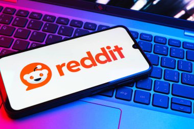 Prag, Çek Cumhuriyeti - 08 01 2025: Dizüstü bilgisayarın üzerinde duran bir cep telefonu Reddit logosunu gösterir. Reddit tartışma, haber ve toplum içeriği için bir platformdur.