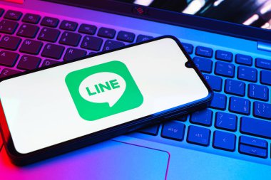 Prag, Çek Cumhuriyeti - 08 01 2025: Dizüstü bilgisayarın üzerinde duran bir cep telefonu Hat logosunu gösterir. Line aramalar, mesajlar ve çokluortam paylaşımı için bir mesajlaşma uygulamasıdır.