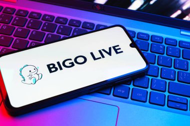 Prag, Çek Cumhuriyeti - 08 01 2025: Dizüstü bilgisayarın üzerinde duran bir cep telefonu Bigo Live logosunu gösteriyor. Bigo Live canlı yayın ve sosyal etkileşim için bir platformdur.